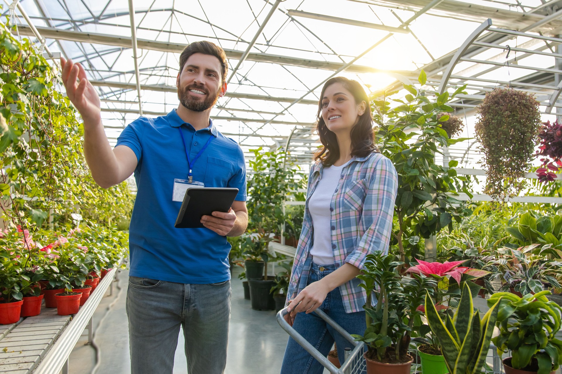 Salesman at retail store offering potted plants and flowers to woman customer
